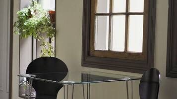 Una habitación con una mesa de vidrio, dos sillas, una planta en maceta y una ventana con vistas.