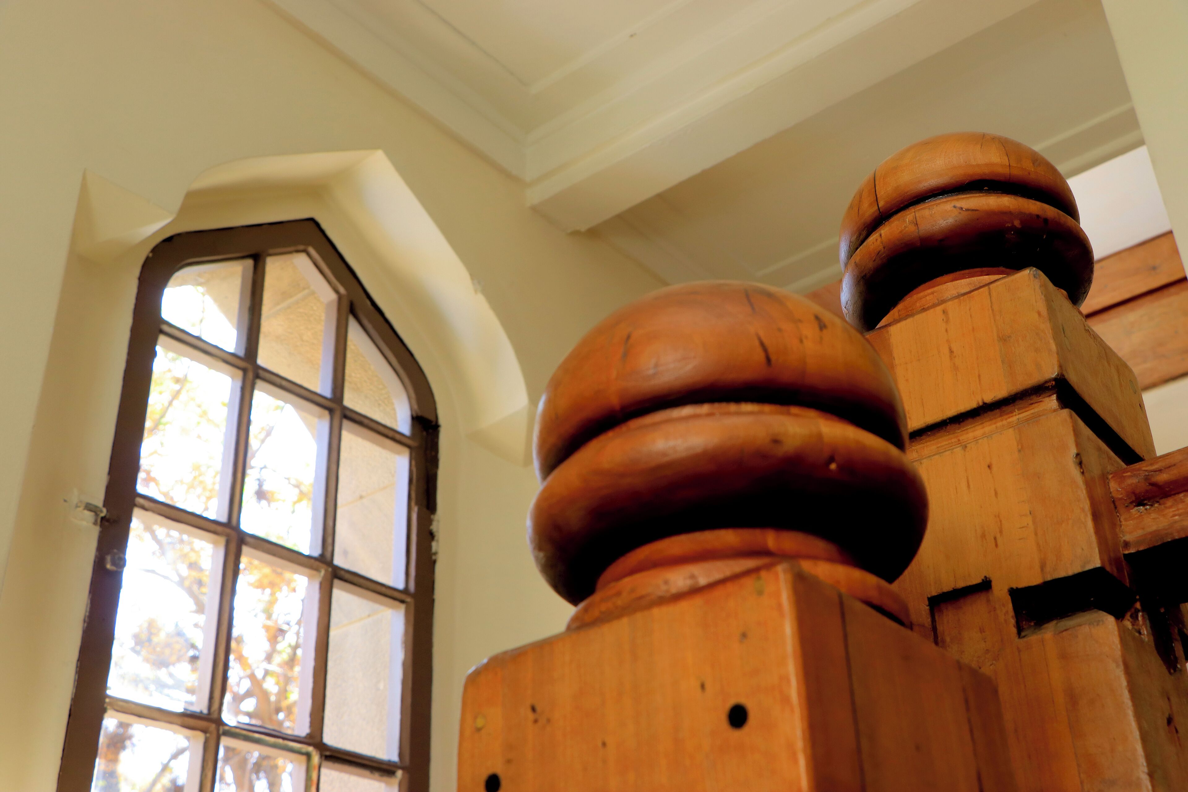 A wooden staircase with a rounded balustrade and a window with multiple panes.