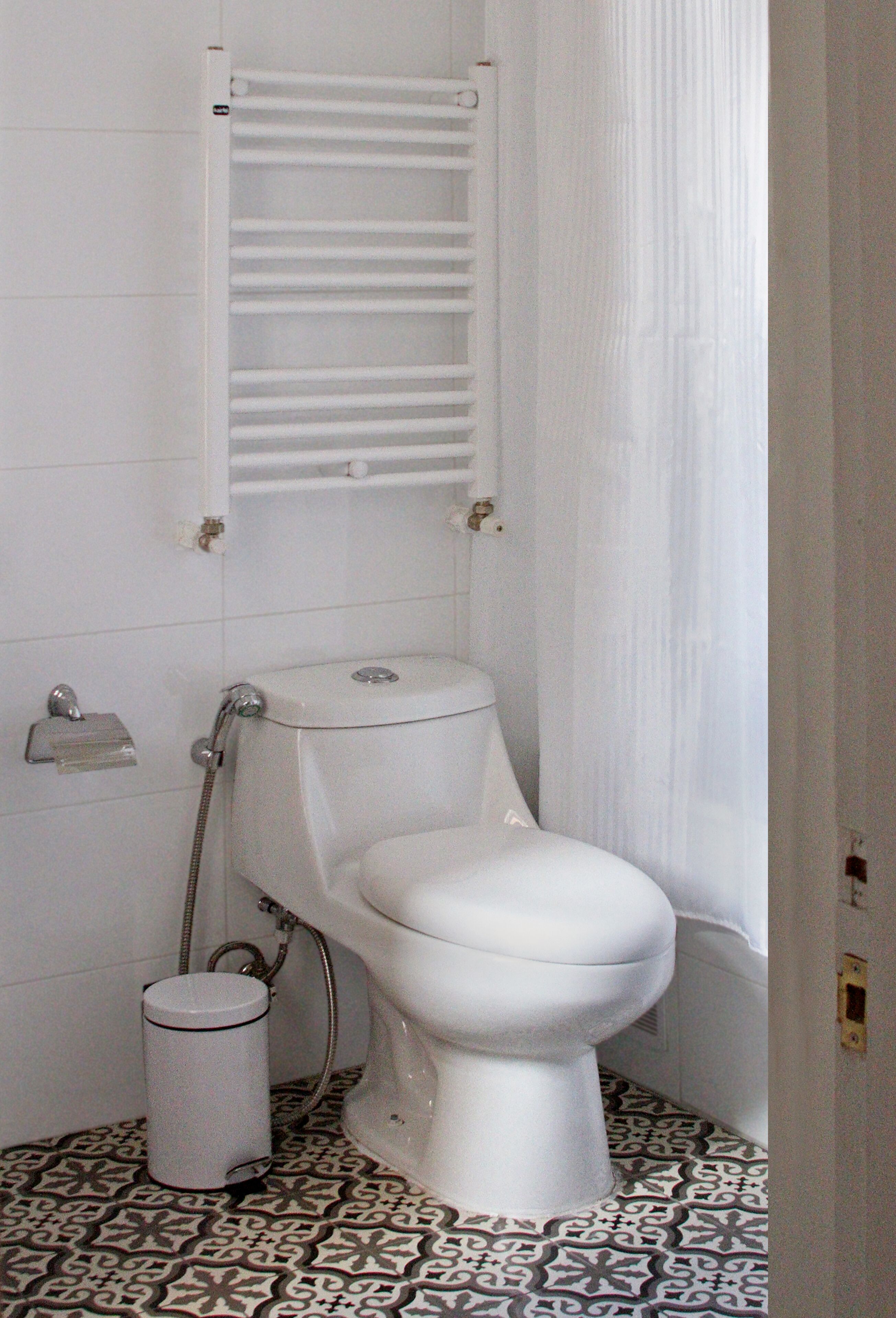 A bathroom with a toilet, a shower, and a patterned floor.