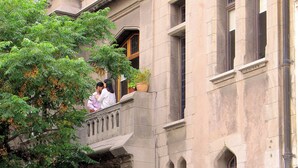 Un edificio histórico con múltiples ventanas, un balcón y un cartel que indica un hotel.
