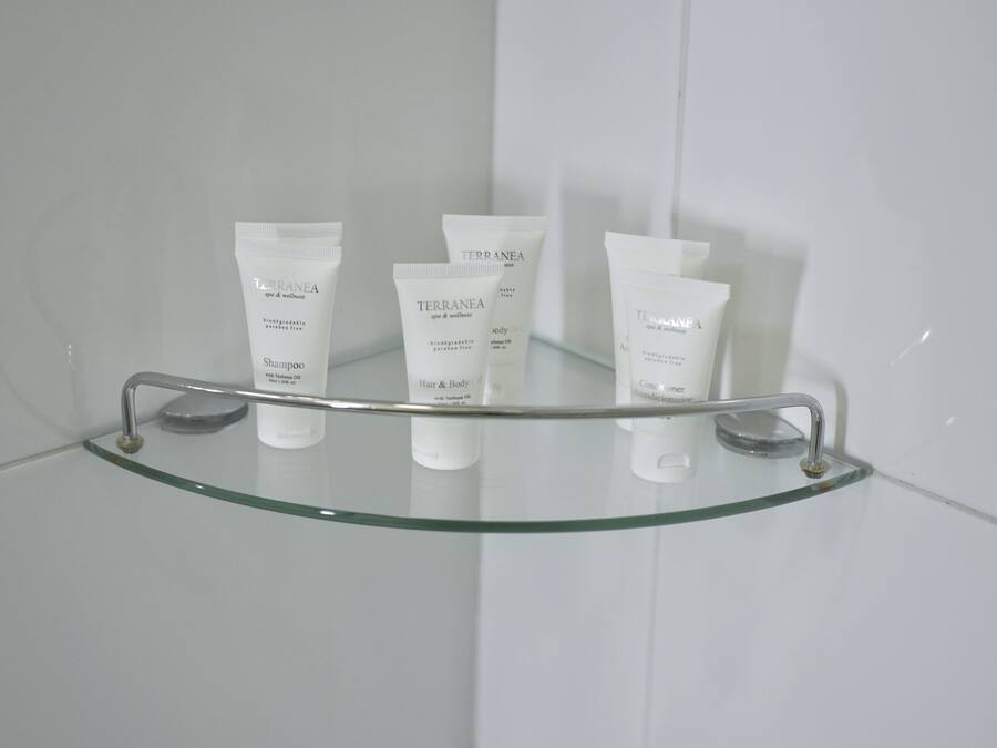 Un estante de baño con tres botellas de productos TERRANEA para spa y bienestar.