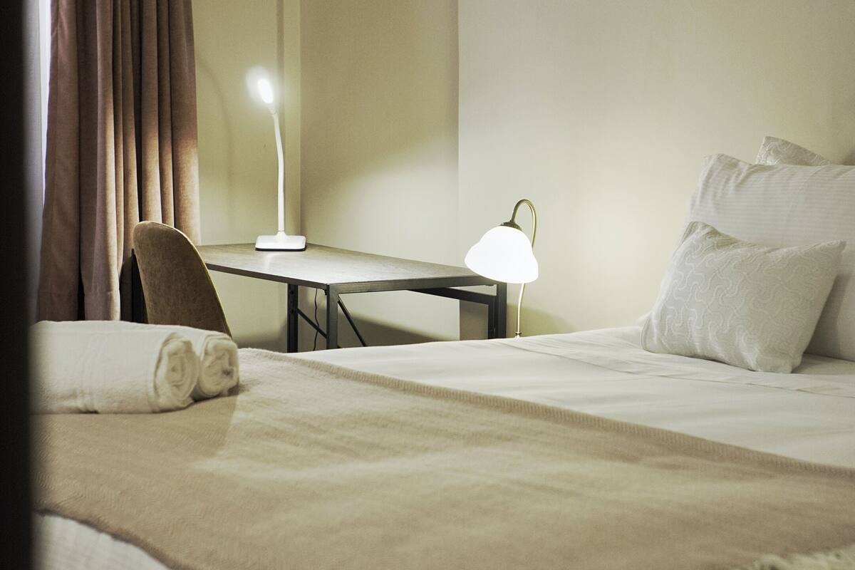 Un dormitorio con cama, escritorio, silla y lámpara.