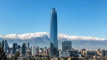 A cityscape with a prominent skyscraper, a variety of other buildings, and a mountain range in the background.