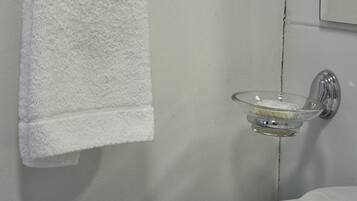 Une salle de bain avec un lavabo blanc, un porte-savon en verre et une serviette blanche suspendue à un porte-serviettes en métal.