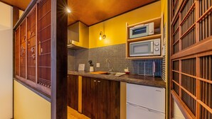 A compact kitchen with wooden cabinets, a microwave, and a sink. - Yadoya Asakusa Sen no Kaze (Tokyo)