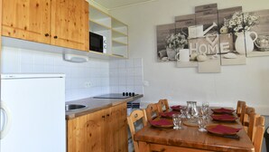 Une cuisine avec des meubles de rangement en bois, un réfrigérateur blanc et une table à manger mise avec des assiettes et des verres.