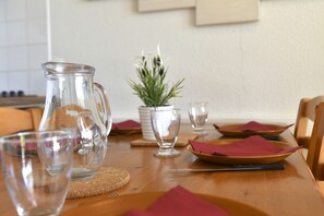 Une table à manger avec une carafe, des verres, des assiettes et une petite plante en pot.