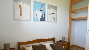 Une chambre à coucher avec un lit en bois, deux tables de chevet, une lampe et trois tableaux encadrés accrochés au mur.