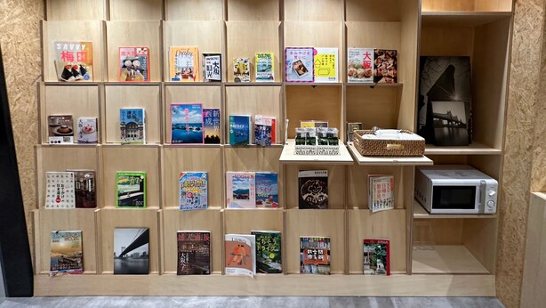 Un présentoir à livres avec divers ouvrages et un four à micro-ondes.