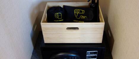 Una caja de madera con papel higiénico y un secador de pelo sobre una encimera.