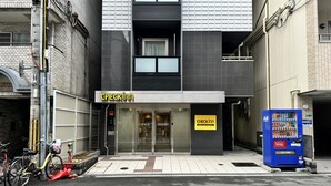 Un hôtel de la chaîne CHECKIN, avec une façade moderne, un distributeur automatique et des vélos garés à l’extérieur.