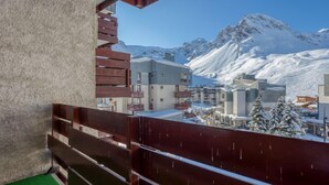 Ein Balkon mit Blick auf schneebedeckte Berge und Gebäude.