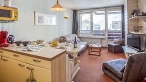 Ein kompakter Wohnbereich mit Küchenzeile, einer Couch, einem Esstisch und einem Fernseher.