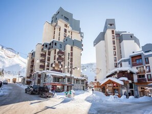 A hotel with multiple floors, a ski lift in the background, and a snowy street. - Le Curling A (Val Claret) by Interhome (Tignes)