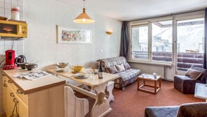 Ein kompakter Wohnbereich mit Küchenzeile, Essbereich und einer Sitzecke mit Sofa und Sesseln.
