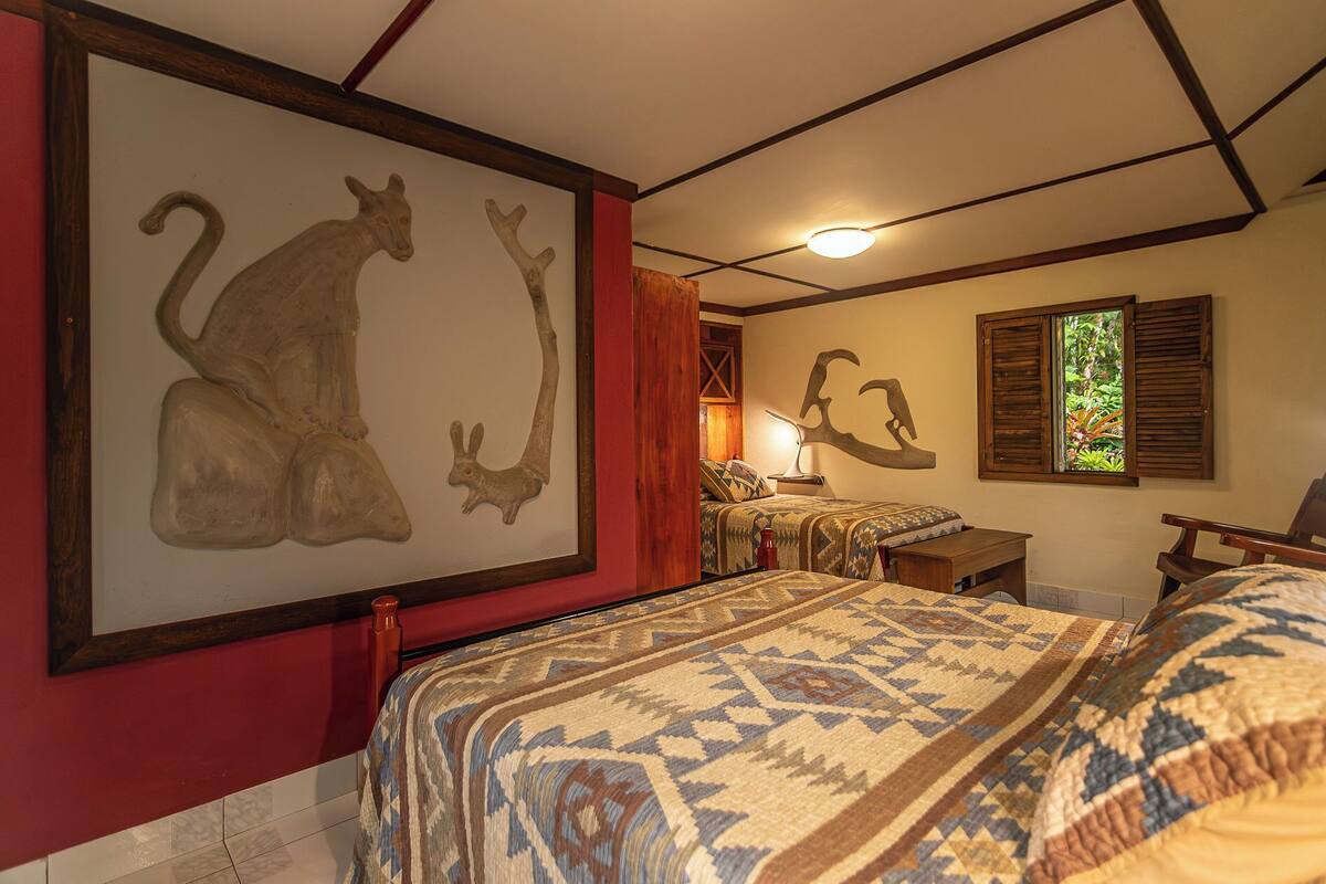 A bedroom with a large wall art of a kangaroo and a wall-mounted lamp.