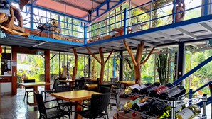A restaurant with a high ceiling, large windows, and a view of greenery. Tables and chairs are arranged for dining. - Talamanca Nature Reserve (Rivas)