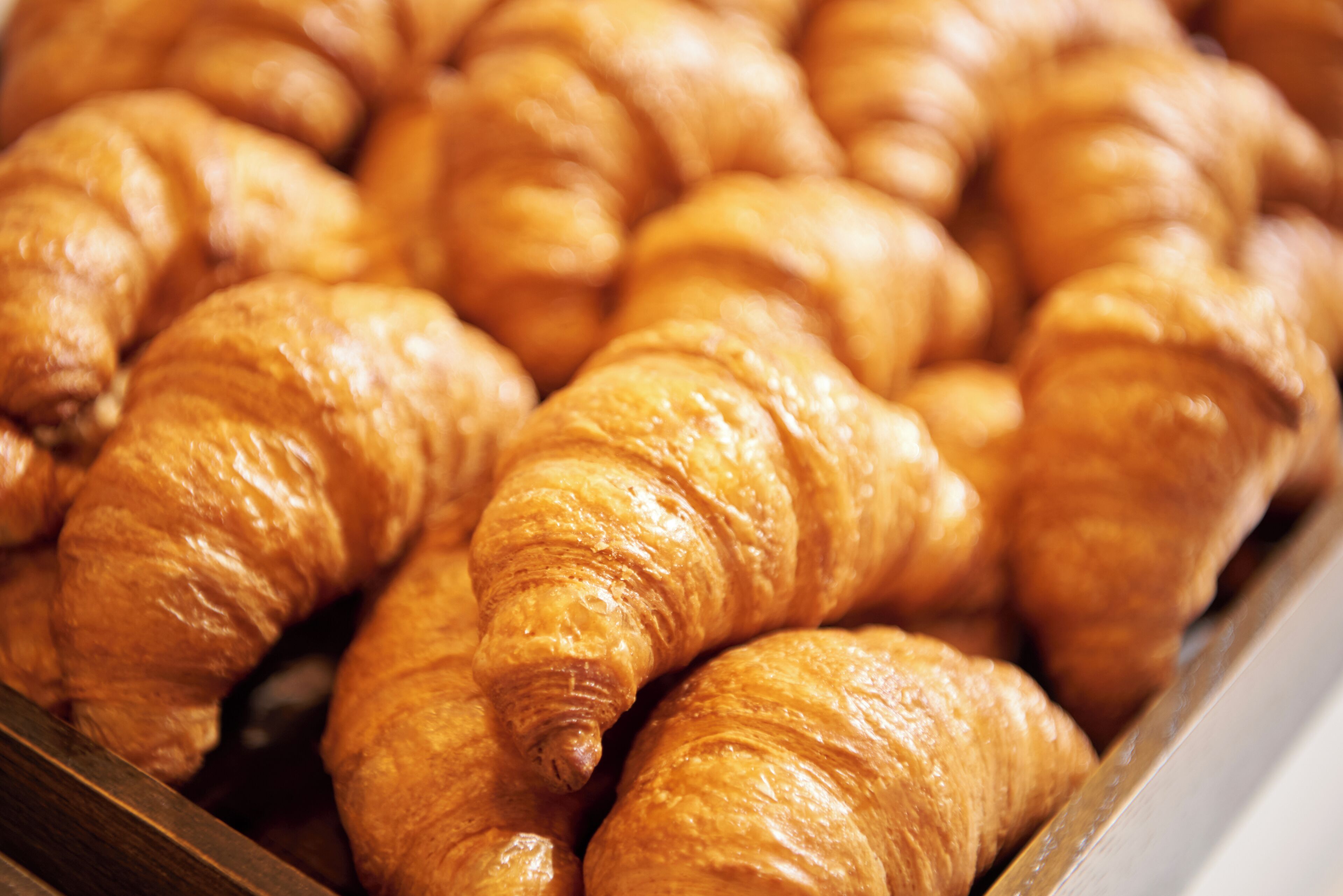 A display of golden-brown croissants arranged closely together.
