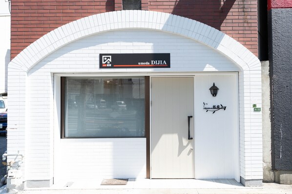 A white building with a black sign above the entrance that reads "umeda DIJIA".