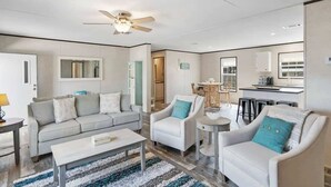 A modern living room with a sofa, armchairs, a coffee table, and a ceiling fan. - On the Canal, by Beach, Kayaks, Dock, Fishing (St. Augustine)