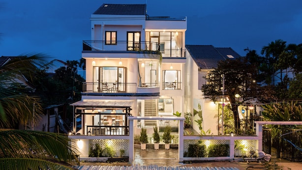A multi-story building with balconies, large windows, and potted plants. - 5 Coconut Homestay Hoi An (Da Nang)