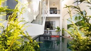 A modern building with a swimming pool, stairs, and outdoor seating. - 5 Coconut Homestay Hoi An (Da Nang)