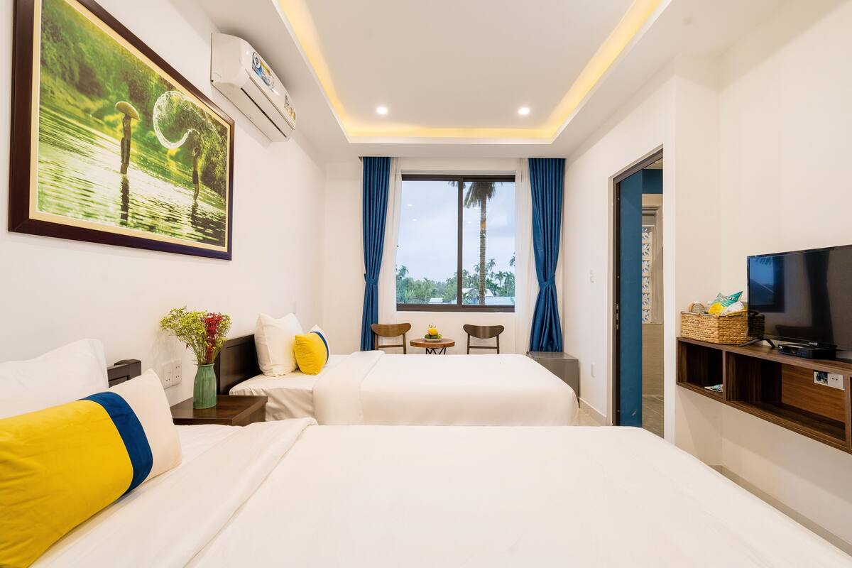 A hotel room with a bed, a TV, a desk, and a window with curtains.