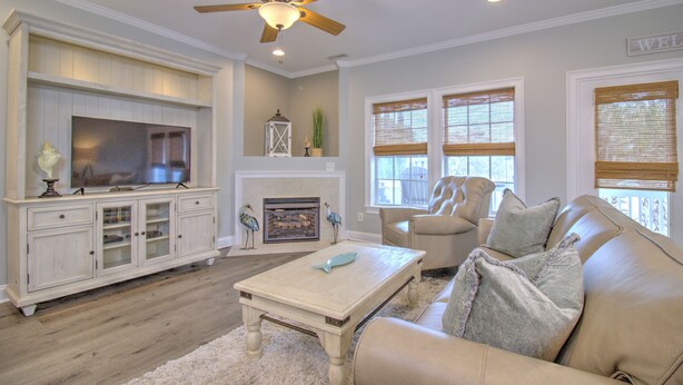 A living room with a fireplace, a television, a ceiling fan, and a sofa.