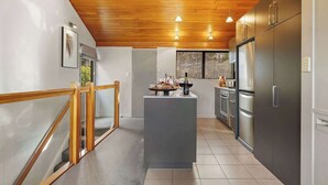 A modern kitchen with a wooden ceiling, stainless steel appliances, and a central island. - SPACIOUS ALPINE LAKE VIEW SPA TOWNHOUSE WALK TO TOWN (Fernhill)