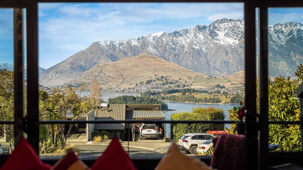 A view from inside a building, looking out at a mountainous landscape with a lake and a parking area with cars. - SPACIOUS ALPINE LAKE VIEW SPA TOWNHOUSE WALK TO TOWN (Fernhill)