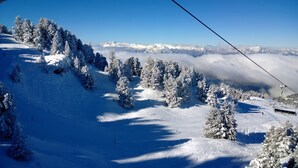 A snowy mountain landscape with a ski lift, snow-covered trees, and a clear sky. - Vercors 1 034-FAMILLE & MONTAGNE studio 4 pers (Chamrousse)