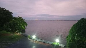 Vista al frente del agua con un paseo pavimentado, farolas y un paisaje urbano distante.