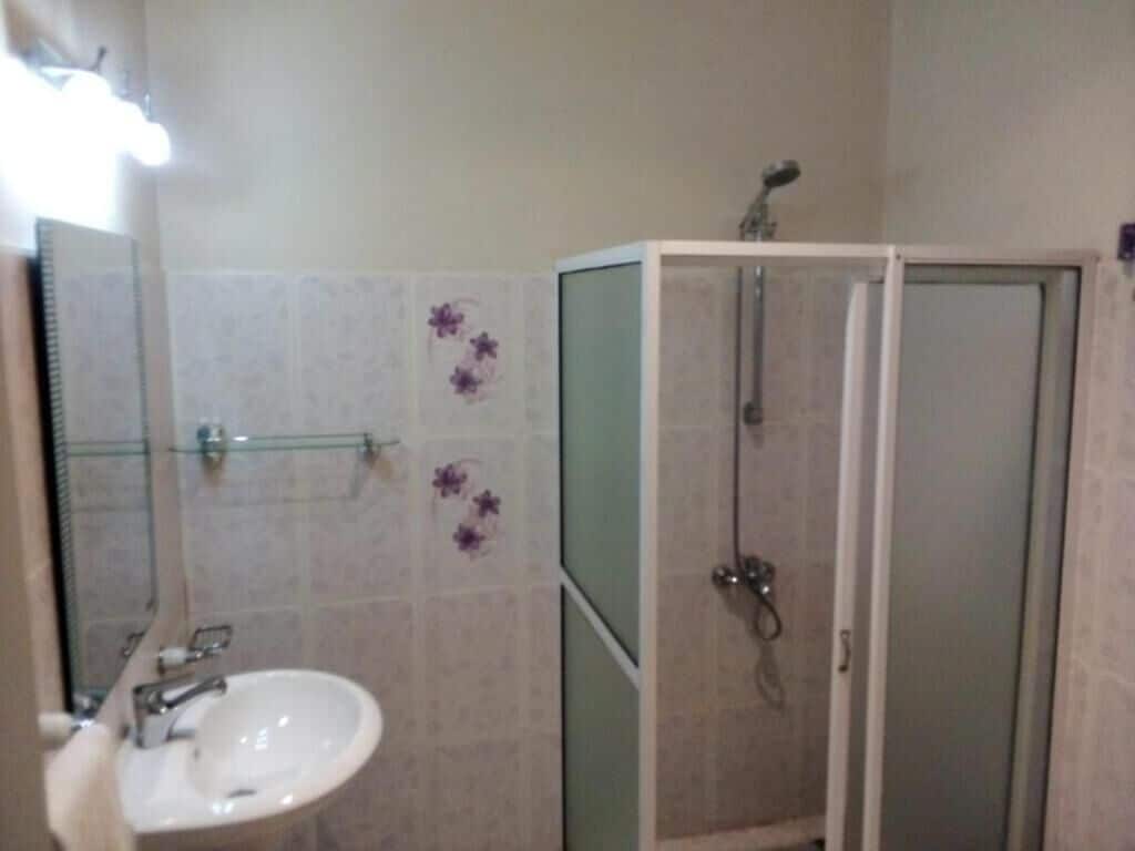 A bathroom with a sink, mirror, and shower enclosure.