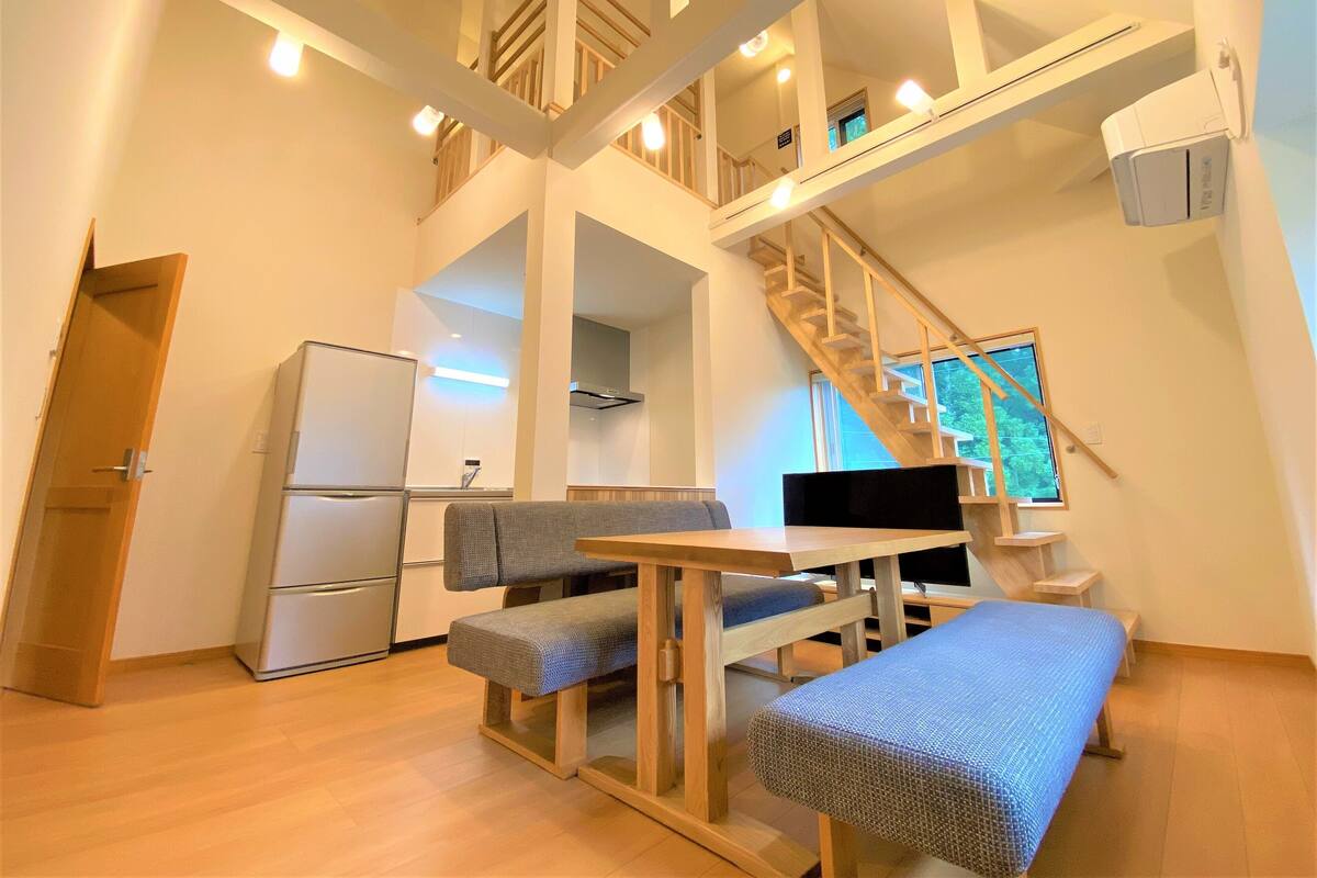 Um interior moderno com cozinha, sala de jantar e escada.