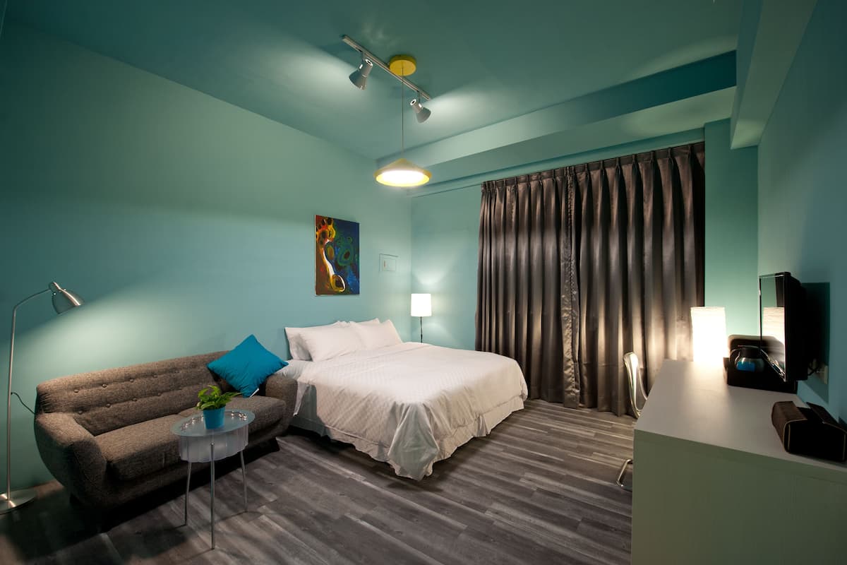 Une chambre d’hôtel moderne équipée d’un lit, d’un canapé, d’un bureau et d’un téléviseur à écran plat.