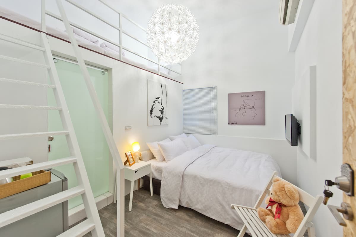 Une chambre avec un lit superposé, une table de chevet avec une lampe, un ours en peluche et des décorations murales.