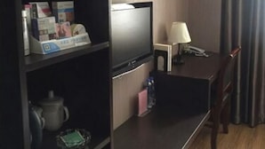 A compact hotel room with a kitchenette, a flat-screen TV, a desk with a lamp, and a chair. - Shanghai Rentail Boutique Hotel (Shanghai)