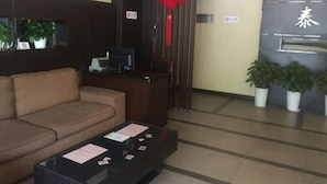 A reception area with a sofa, a desk, a computer, and a red decorative item on the wall. - Shanghai Rentail Boutique Hotel (Shanghai)