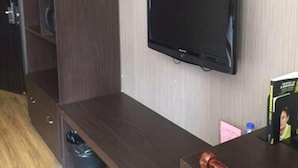A room with a dark wood cabinet, a flat-screen TV mounted on the wall, and a wooden table with a chair. - Shanghai Rentail Boutique Hotel (Shanghai)
