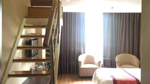 A hotel room with a wooden staircase, a bed with a red blanket, two chairs, and a window with curtains. - Shanghai Rentail Boutique Hotel (Shanghai)