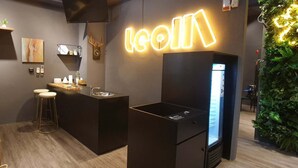 A modern bar area with a neon sign, a refrigerator, and a green wall with plants. - Leo 111 - Yancheng Pier 2 (Kaohsiung)