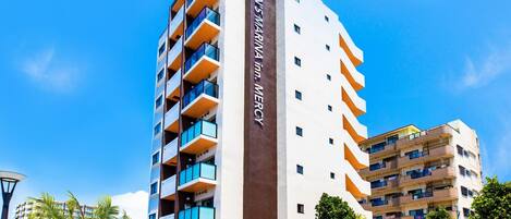Un hôtel à plusieurs étages, doté d’une grande enseigne verticale sur laquelle on peut lire : « IEMEN’S MARINA Inn MERCY ».