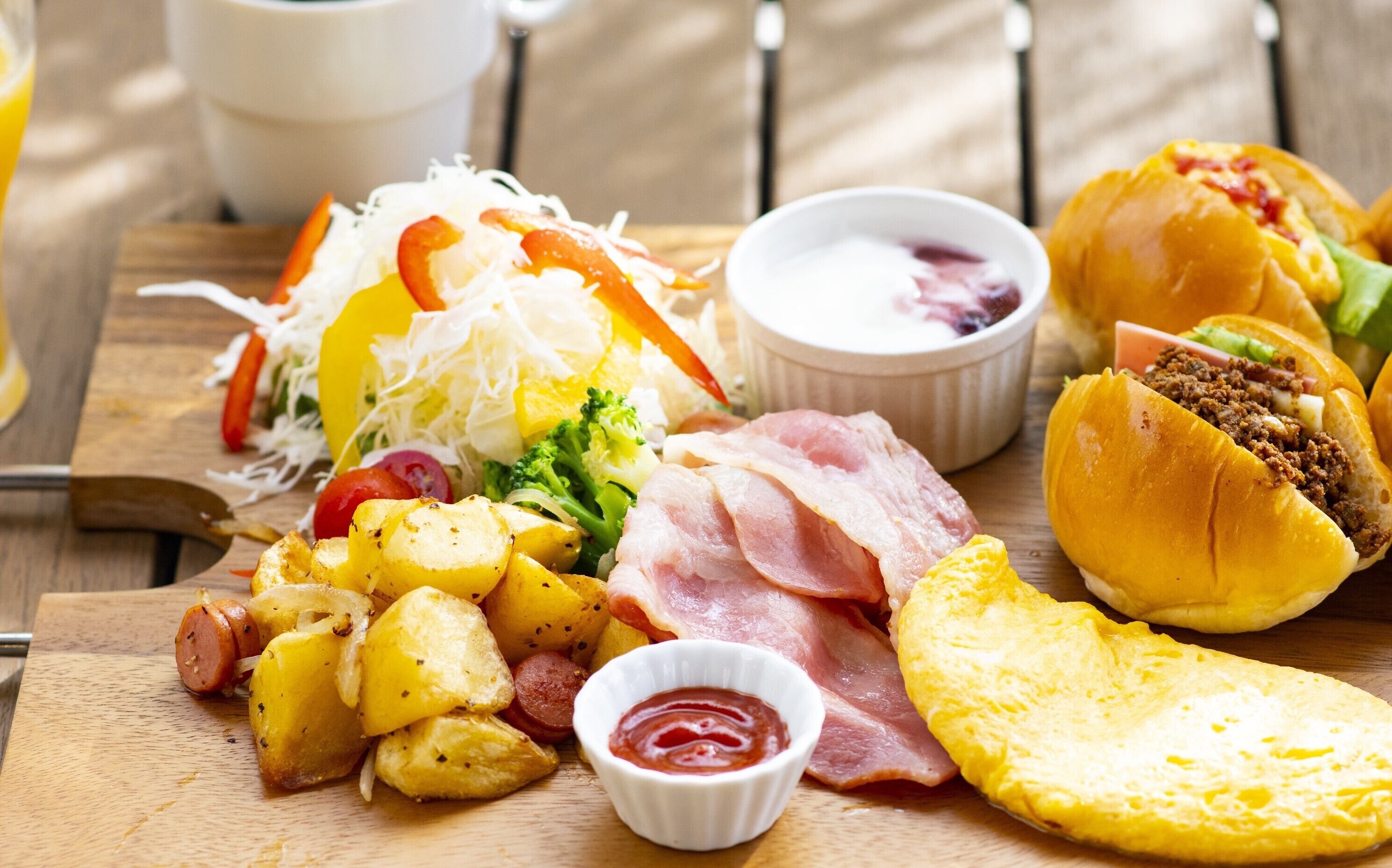 Un plato con diferentes opciones como patatas, jamón y una hamburguesa.