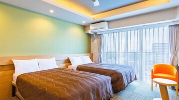 Habitación de hotel con dos camas, ventilador de techo, equipo de aire acondicionado, ventana con cortinas y una silla naranja pequeña.
