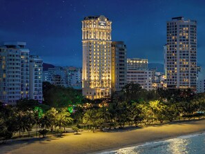 A high-rise hotel with a classic architectural design, situated by a beach with palm trees and a view of the ocean. - Mercure Nha Trang Beach (Nha Trang)