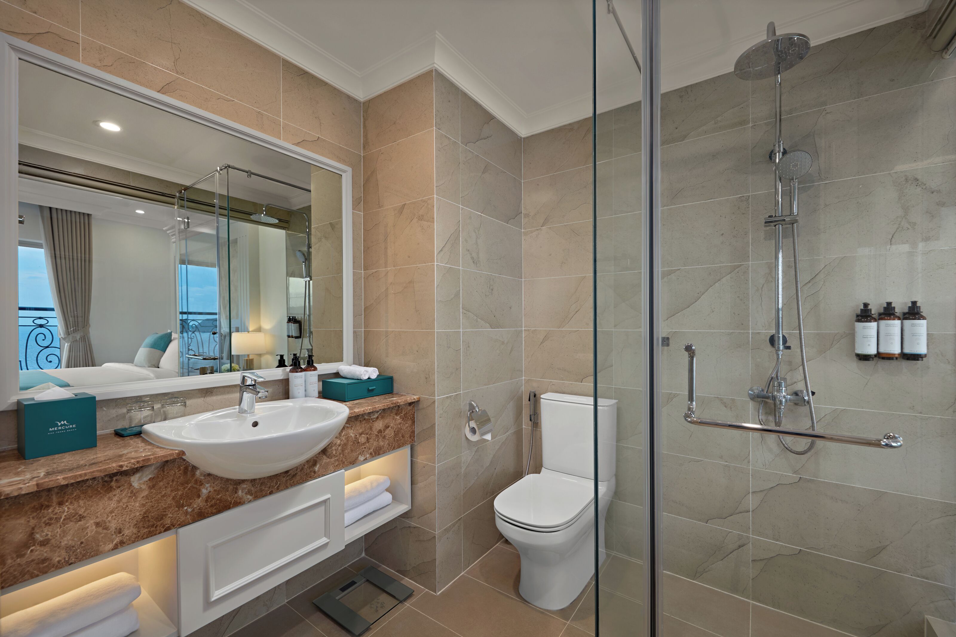 A modern bathroom with a glass-enclosed shower, a white sink, and a large mirror.