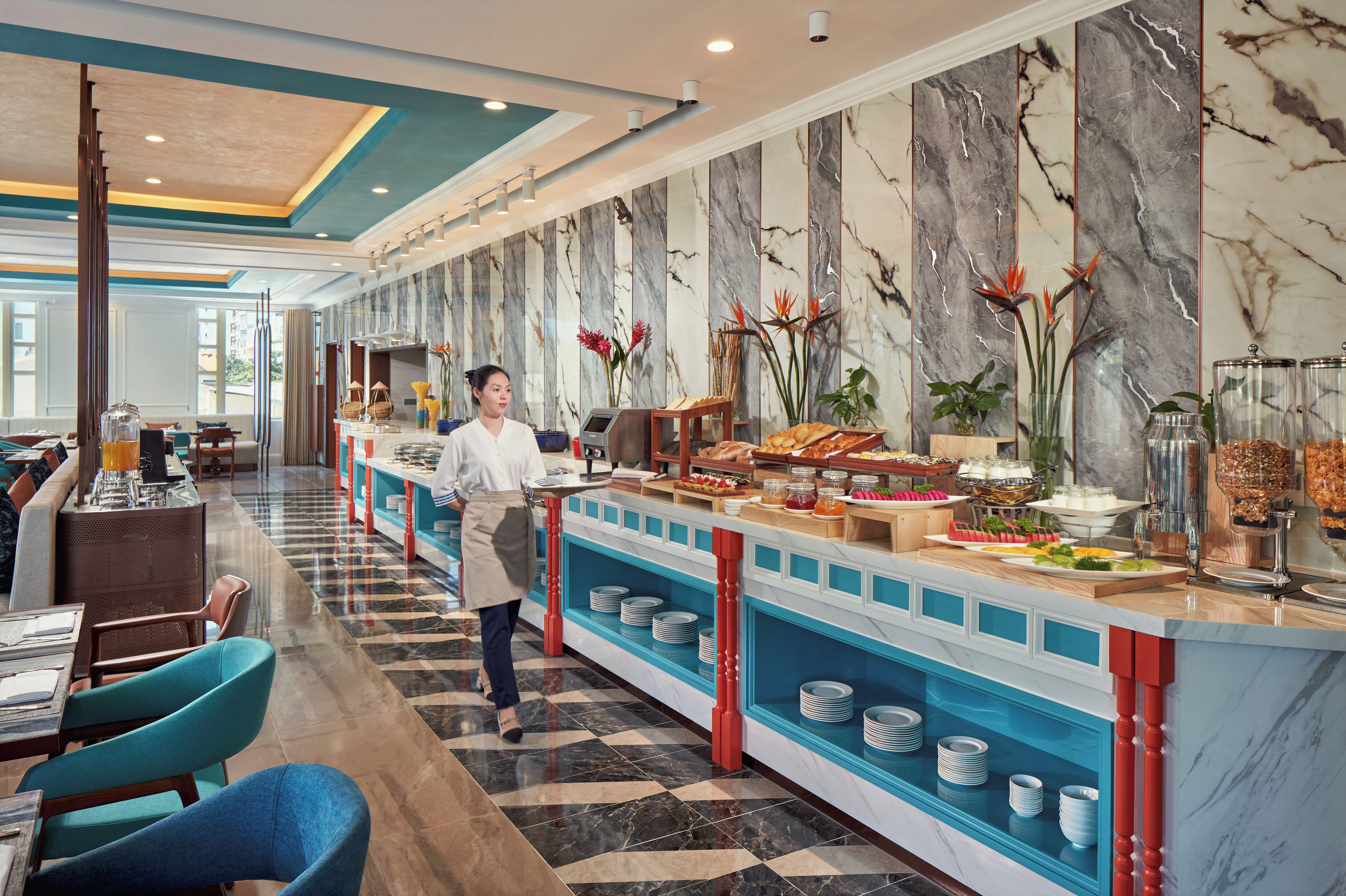 Un hall d’hôtel avec un mur en marbre, un espace buffet et des coins salon.