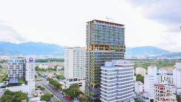 Un hotel de varios pisos con balcones, rodeado de otros edificios y montañas al fondo.