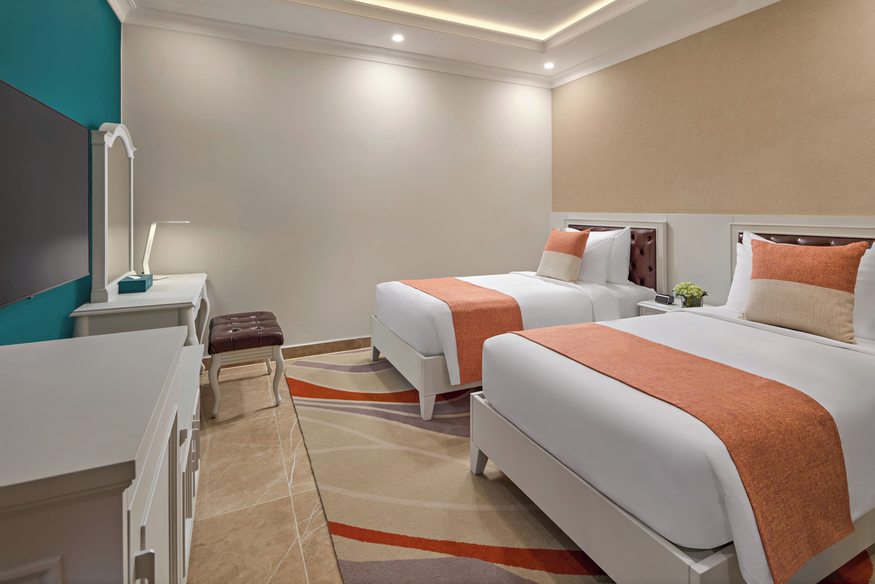 Une chambre d’hôtel avec deux lits, un bureau, une chaise et un miroir.