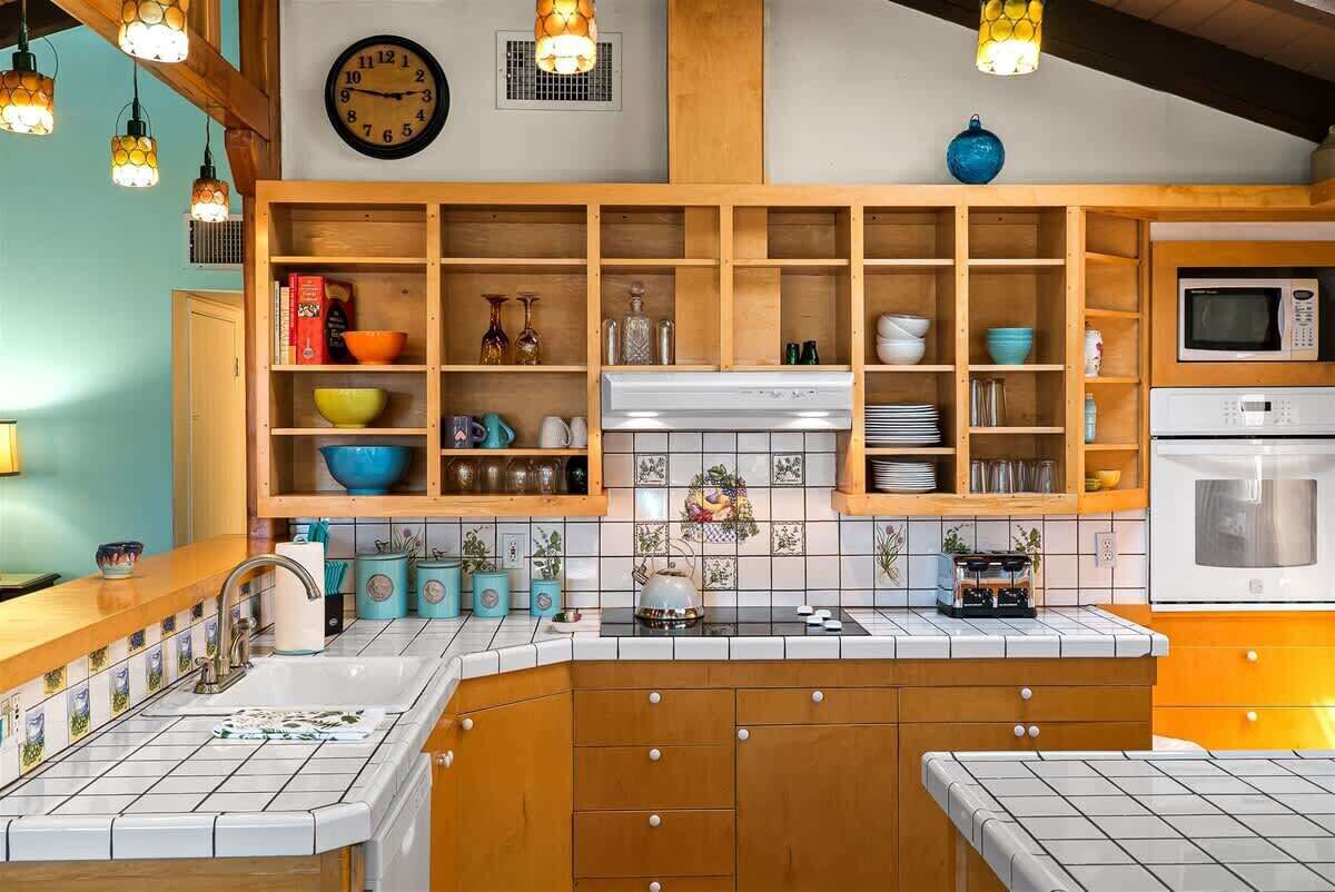 A kitchen with wooden cabinets, a microwave, and a clock on the wall.